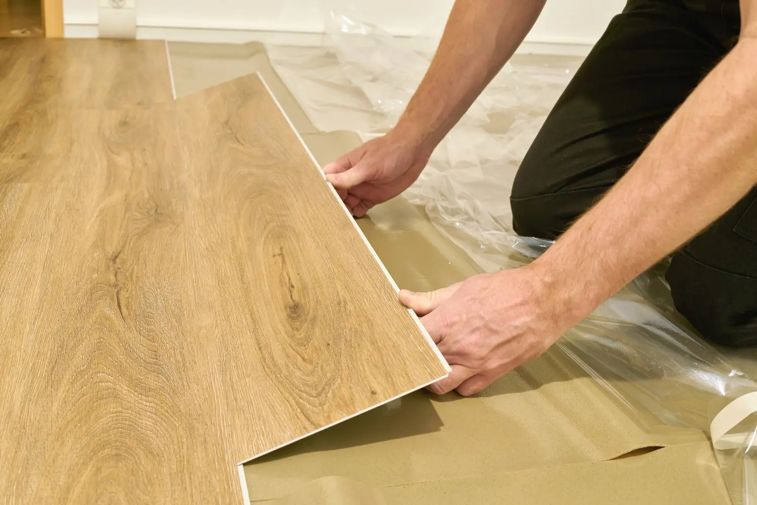 Handwerker beim Renovieren einer Wohnung und beim Verlegen von einem Klick-Vinyl Bodenbelag